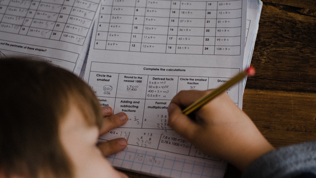 Una bambina concentrata su un libro di scuola: la fatica con i numeri è spesso accompagnata da un calo di autostima