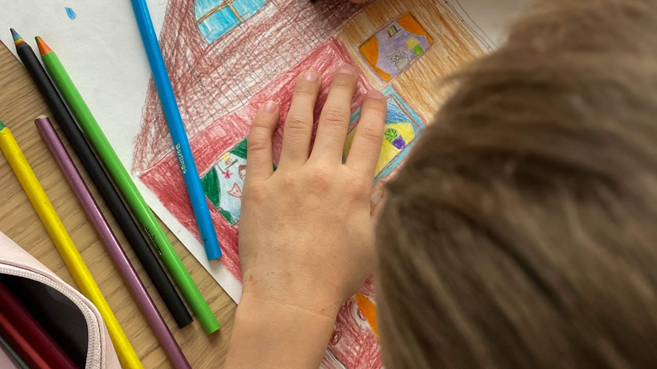 Una bambina al banco con quaderno e matite colorate: dalla terza elementare gli errori ortografici dovrebbero calare in modo visibile