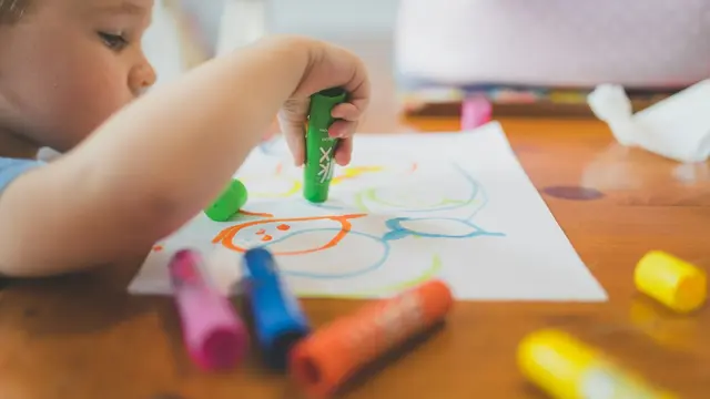 Un bambino disegna con i colori seduto a un tavolo di legno: la valutazione neuropsicologica dei bambini passa da prove che somigliano a giochi e compiti