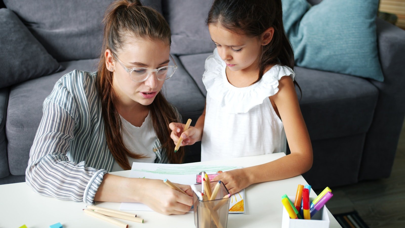 Una madre e una bambina disegnano insieme a un tavolino di casa: il colloquio iniziale della valutazione neuropsicologica ricostruisce la storia del bambino con chi lo conosce meglio